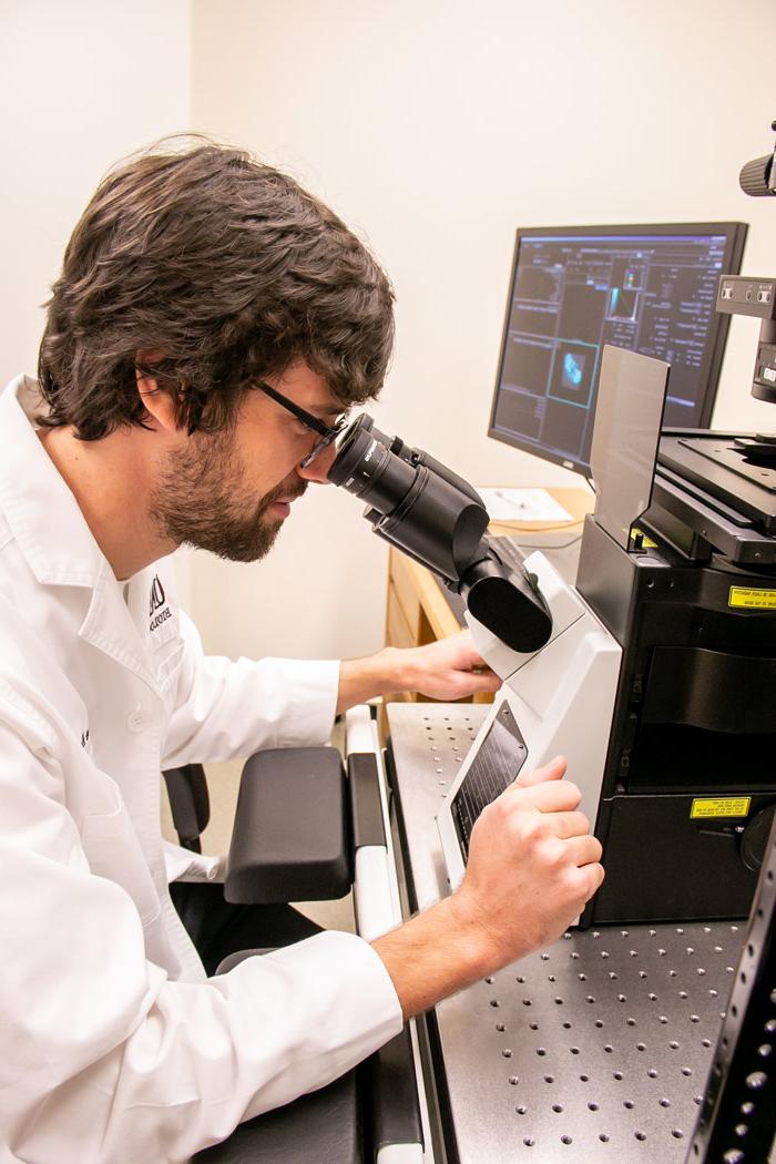 M.S. 生物学学生Blase Rokusek在体育菠菜大平台生物实验室通过显微镜观察.